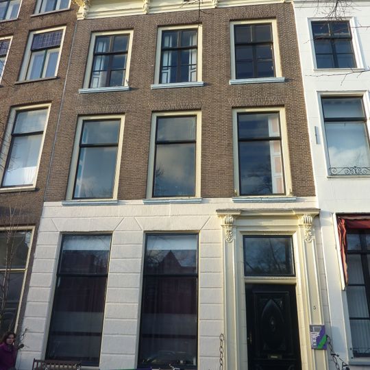 Pand met gevel met rechte kroonlijst. Hardstenen stoep met palen