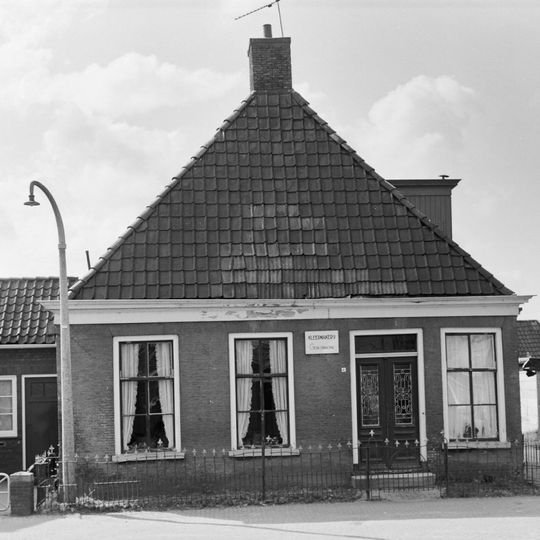 Eenvoudig pand met zesruitsvensters onder zadeldak met voorschild waarboven topschoorsteen