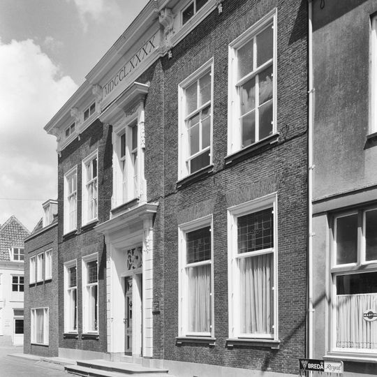 Fors L-vormig pand onder schilddak met gepleisterde rechte gevels. Kroonlijst met klossen