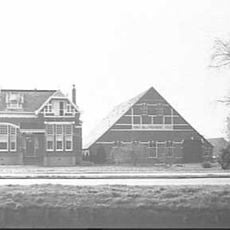 Villa, opgetrokken in baksteen op een gepleisterde plint vanaf vierkante grondslag over één, opvallend hoge, bouwlaag onder een met leien gedekt afgeknot schilddak