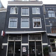 Voormalig koetshuis met gevel onder rechte lijst waarboven een dwarsdak