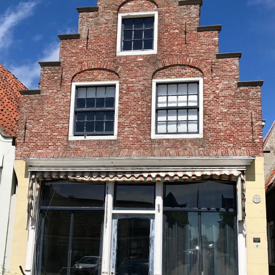 Pand onder zadeldak tegen gepleisterde trapgevel met verhoogd achterhuis tussen twee puntgevels