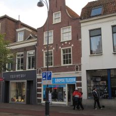 Pand met klokgevel, voorheen trapgevel, toegespitste bogen boven vensters met natuurstenen blokken, grote leeuwenmaskers