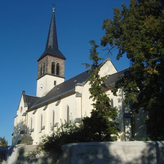 Kirche, fünf Grabmale, eine Grabanlage und Denkmal für die Gefallenen des Ersten Weltkrieges auf dem Kirchhof, zwei Steinbänke und ein Grabmal auf dem Friedhof sowie gesamte Einfriedungsmauer mit fünf schmiedeeisernen Toren (Einzeldenkmale zu ID-