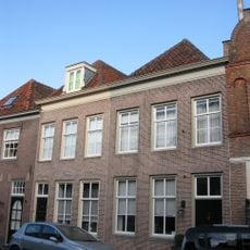 Huis onder schilddak en met lijstgevel, boven met zesdelige schuiframen. Met eigen stoep