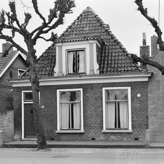 Eenvoudig pand zonder verdieping onder zadeldak met voorschild en grote dakkapel met bloklijst en pilasters