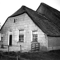 Boerderij met karakteristieke hoofdvormen: lager woonhuis onder rieten wolfdak en met gepleisterde gevel, waarin vensters met twintig, twaalf- en zesruitsschuiframen