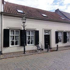 Wit dorpshuis, zadeldak van rode pannen met nok evenwijdig aan de gevel