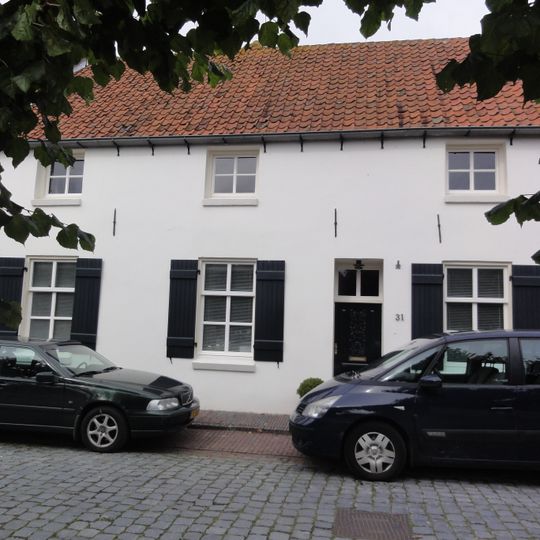 Dwarshuis onder zadeldak tussen zij-topgevels en met gepleisterde lijstgevel