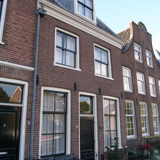 Dubbel pand met brede klokgevel, aan de top boogstuk met wapensteen