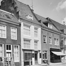 Pand met verdieping en zadeldak, dat links wordt afgesloten door een trapgevel met ezelsrugafdekkingen