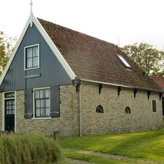 Diep smal woonhuis onder zadeldak, topgevel met houten voorschot