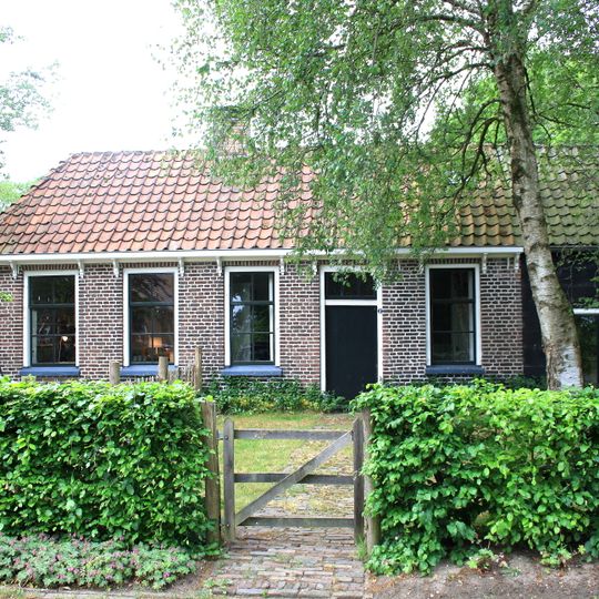 Daglonershuisje met houten staldeel onder pannengedekt schilddak