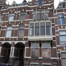 Pand in neo-renaissance trant met rechts topgevel. Brede houten erker op korbelen. Gevelversiering met banden en blokken. Links getoogde ingangspartij