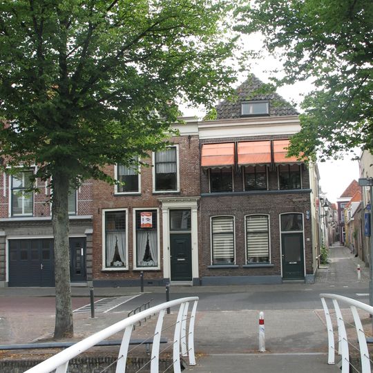 Hoekpand met eenvoudige lijstgevel en zonneblinden op de verdieping