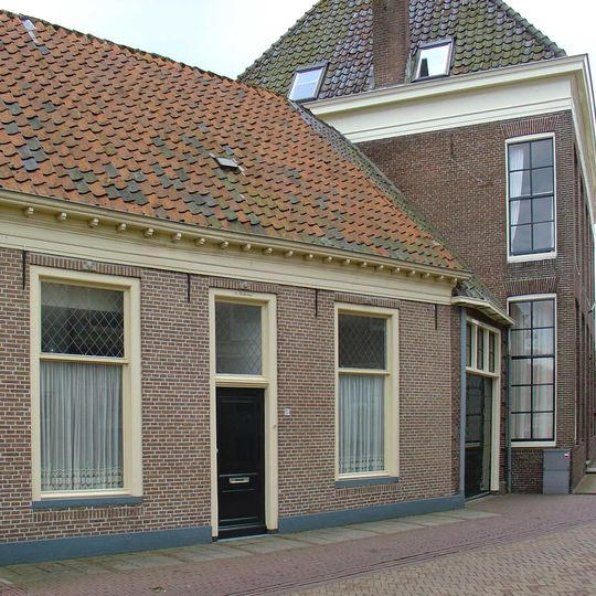 Eenvoudig pand met gewijzigde vensters onder zadeldak achter gevel met nr. 53