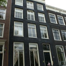 Pand met gevel onder rechte stenen lijst en gebeeldhouwde attiek, met gebeeldhouwde stoep en deurpartij