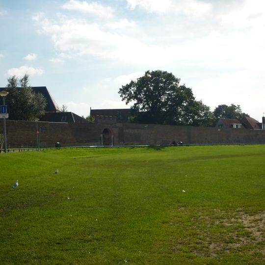 Langgerekt gedeelte van de vestingmuur van hotel monopole tot voorbij het Blokhuis met spitsbogig poortje met kantelen