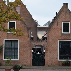 Hofje, dat aan de grachtzijde is afgesloten door twee gepleisterde puntgevels