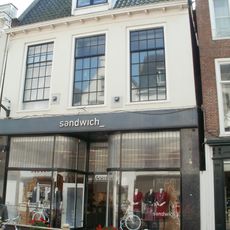 Pand met hoge verdieping onder dwarskap tussen topgevels