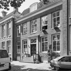 Huis met sobere lijstgevel en stoep, geen versiering boven de deur, tegenhanger van nr 6