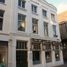 Samengetrokken uit twee panden die aan de Wijnhaven een puntgevel met vlechtingen en een lijstgevel hebben. Dak vernieuwd