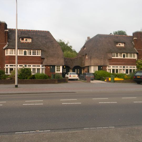 Woonblok van twee dubbele woonhuizen in Amsterdamse School-stijl, met elkaar verbonden door een dubbele garage