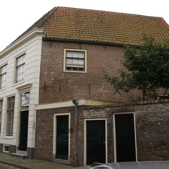 Huis onder dwars schilddak en met lijstgevel waarin ramen met kleine roedenverdeling