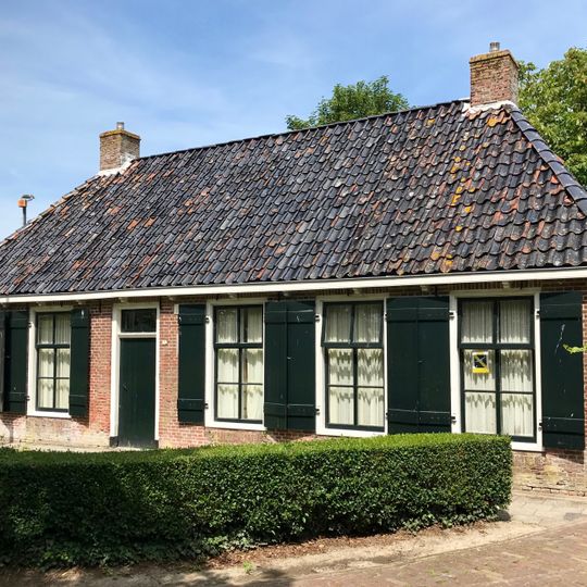 Pand met goot op klossen onder schilddak met hoekschoorstenen