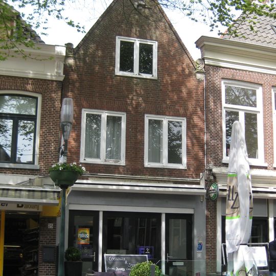 Huis met geverfde eenvoudige gevel met rechte kroonlijst onder zadeldak