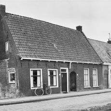 Hofje met hoofdgebouw onder zadeldak evenwijdig aan de straat tussen twee topgevels (vormt een geheel met nr. 37)