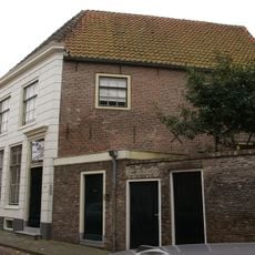 Huis onder dwars schilddak en met lijstgevel waarin ramen met kleine roedenverdeling