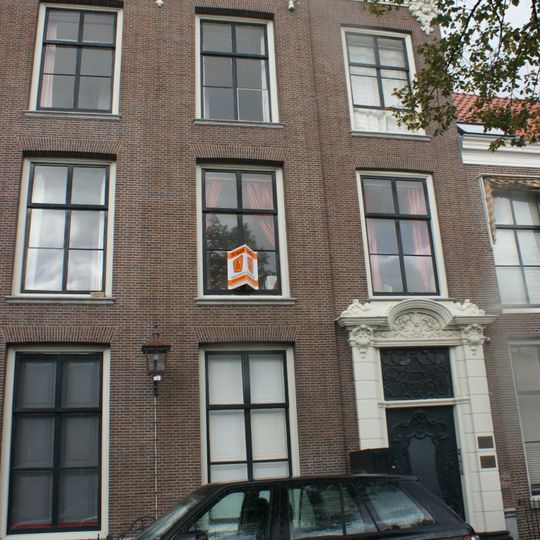 Statig patriciershuis, ingangsomlijsting met zwaar gebeeldhouwde deur, bovenlicht, consoles fraai gesneden; rechte kroonlijst, fraai stoephek régence met krullen en initialen