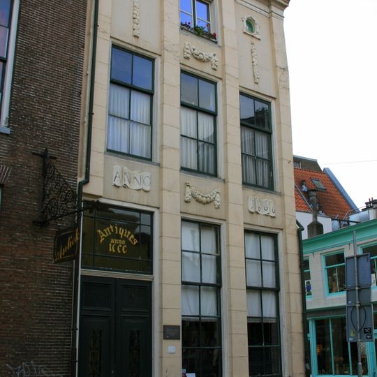 Pand met gepleisterde gevel zonder top, vier doorgaande pilasters en gebeeldhouwde festoenen en oeil de boeuf's