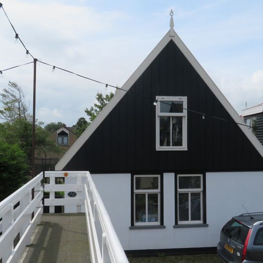 Pand onder zadeldak. Gepleisterde gevel waarboven houten geveltop