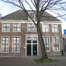 Rechter helft van ondiep woonhuis met eenvoudige bakstenen gevel, geleed door middenrisaliet, waarin ingangspartij; bestemd voor annex van het Westfries museum