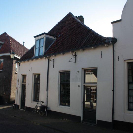 Huis met bakstenen lage gevel met rechte kroonlijst. Vormt een geheel met nr 43