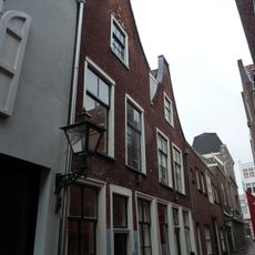 Pand met verdieping onder zadeldak met halsgevel waarin ongedeelde- en 6-ruitsschuifvensters in geprofileerde omlijstingen; 9-ruitsschuifvenster in top