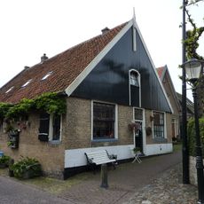 Fors gaaf hoekpand met houten voorschot waarin luik; vensters met roedenverdeling