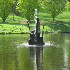 Fontána z kamene a kovu v jezírku v Husových sadech v Sokolově