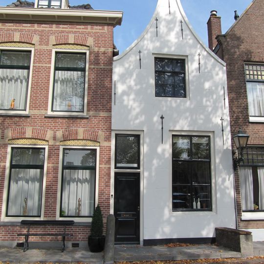 Huis met gepleisterde tuitgevel met schuiframen in stijl