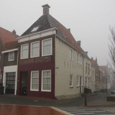 Hoekpand onder zadeldak tegen achtertop en voorgevel met kroonlijst en voorschild met topschoorsteen