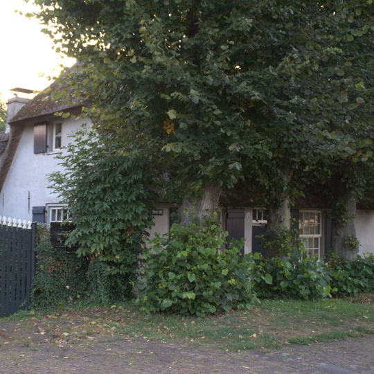 Boerderij uit de 18e eeuw met rieten wolfdak, gepleisterde voorgevel, waarin twee vensters met luiken en 16-ruitsschuiframen en vlechtingen in de zijgevels