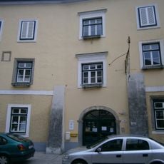 Gasthaus Tröls, ehem. Zur Goldenen Sense mit Wirtshausschild und Stadtmauerteil