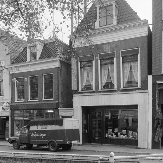 Eenvoudig pand met geblokte kroonlijst onder diep zadeldak met voorschild en dakkapel