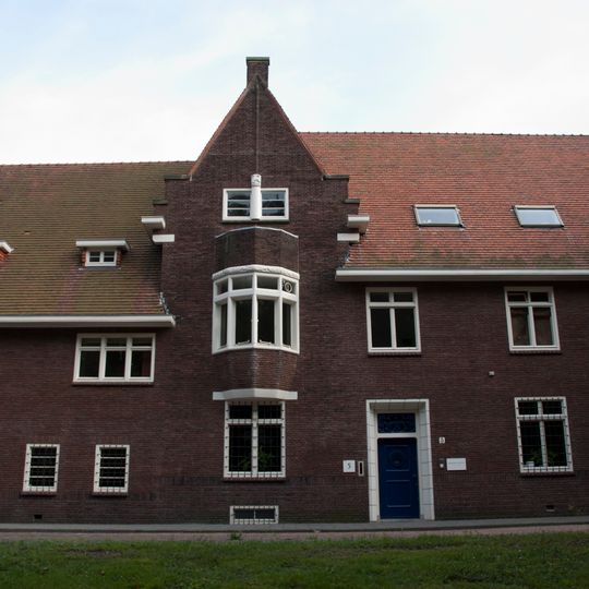 Herenhuis met voormalige personeelswoning gebouwd in de stijl van de Delftse School met expressionistische details zoals die voorkomen in de Amsterdamse School