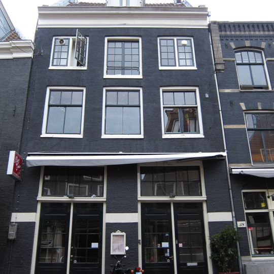 Voormalig koetshuis met gevel onder rechte lijst waarboven een dwarsdak