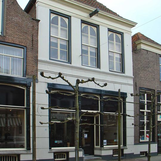 Huis met gepleisterde lijstgevel met empire-schuiframen op de verdieping