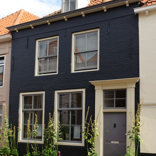 Pand met lijstgevel van midden 19e-eeuws karakter. Deuromlijsting met gecanneleerde pilasters en hoofdgestel. Schilddak