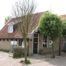 Pandje aan de rooilijn gelegen met houten voorschot waarin vlieringluik